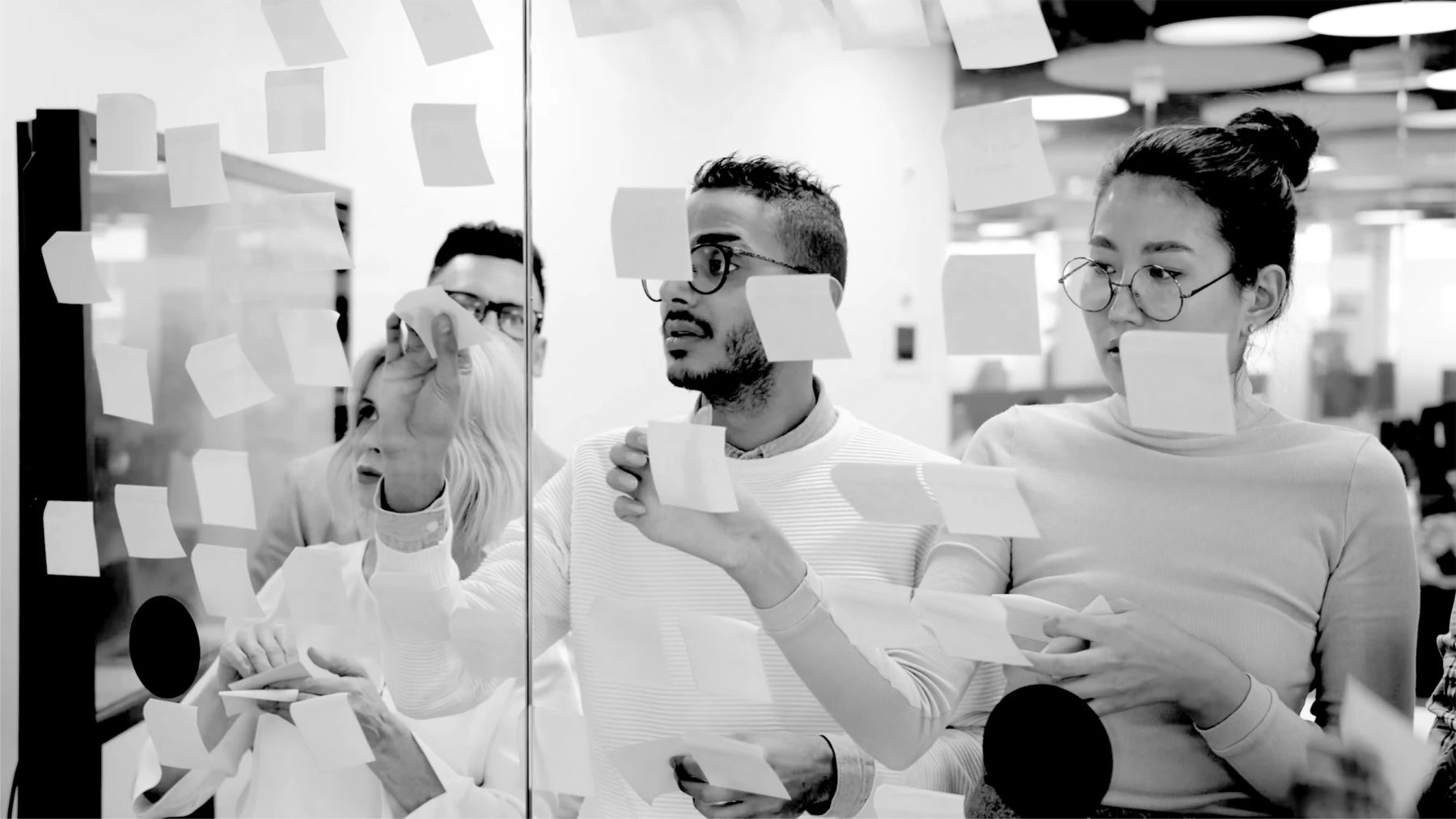 A team sorting sticky notes on a glass wall