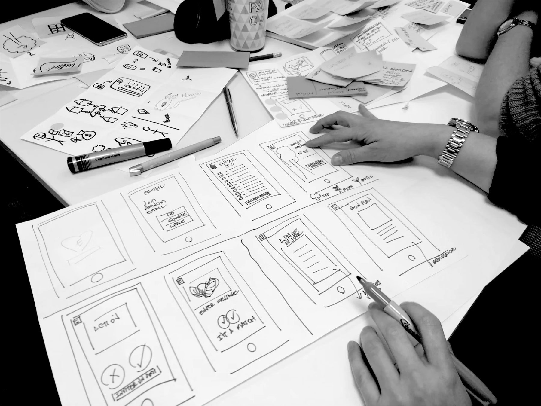 Hand-drawn phone screens sketched as a storyboard on a workshop table