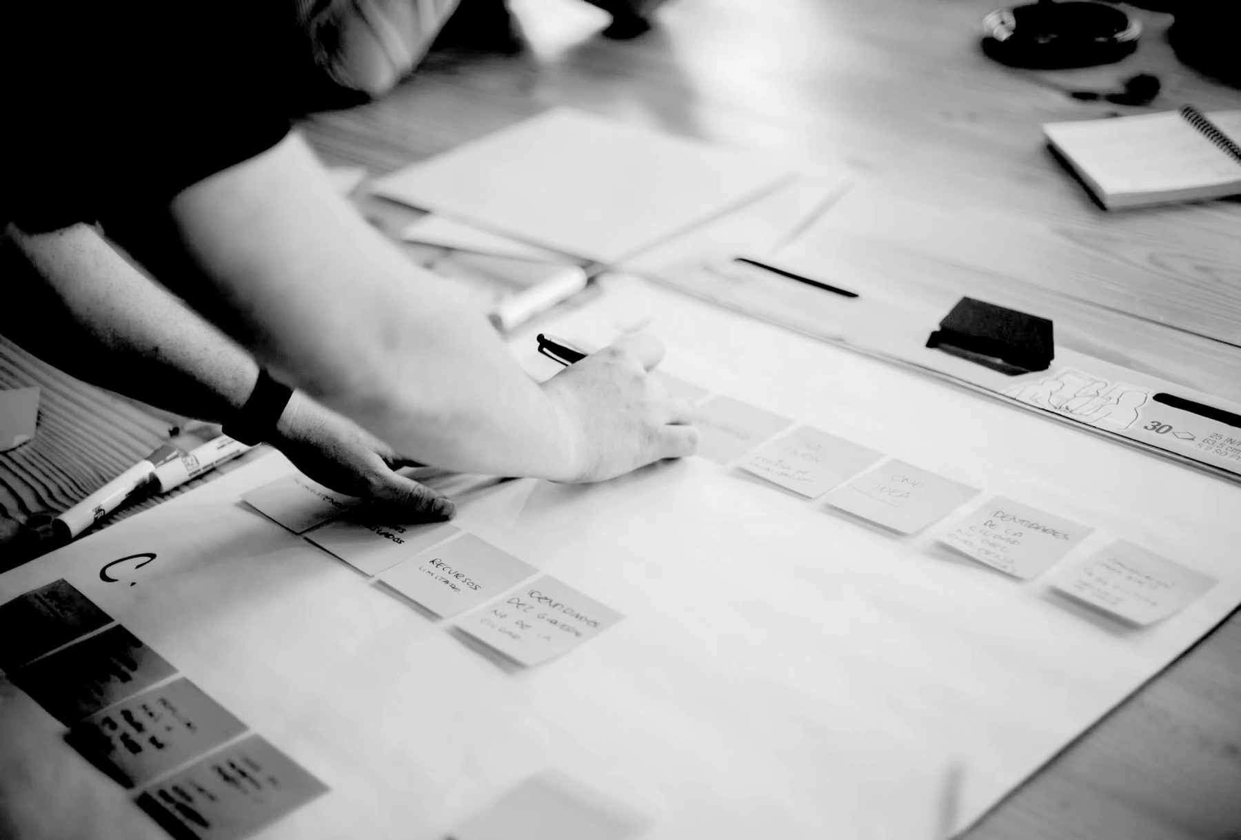A facilitator arranging sticky notes along a large paper map on a workshop table